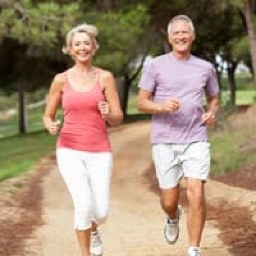 Elderly couple jogging outdoors for health and wellness.