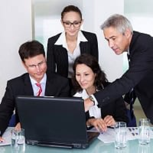 Professional team working together on a laptop in a meeting room.